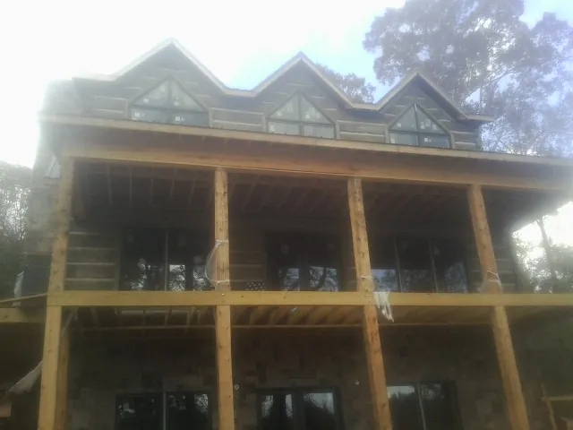 Dormers and porch framing on a large log home under construction — Roof Coating work by our crew in Wawaka