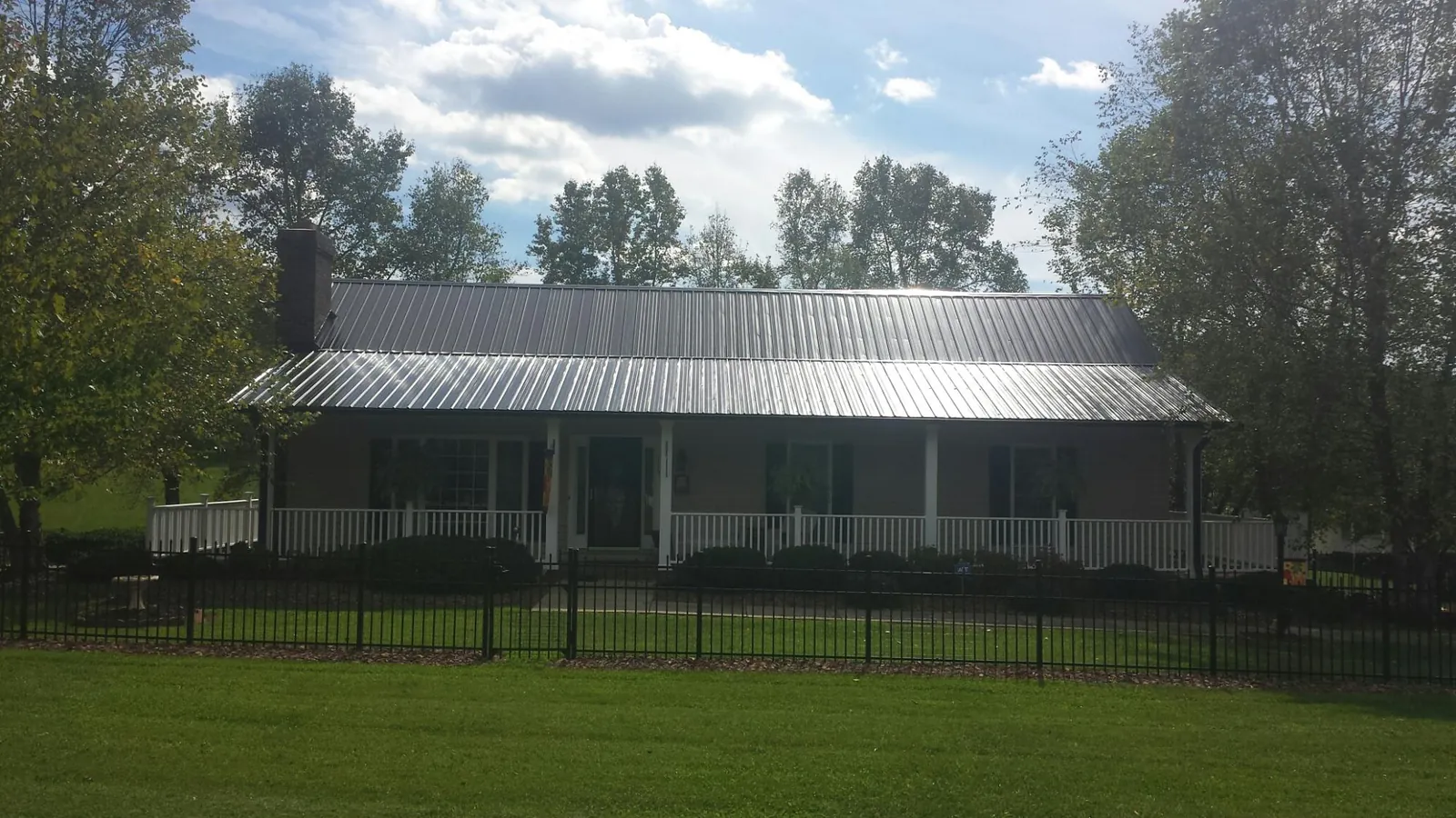 Gray metal roof on a brick ranch with a full width front porch — Gutter Guard Installation work by our crew in Wawaka
