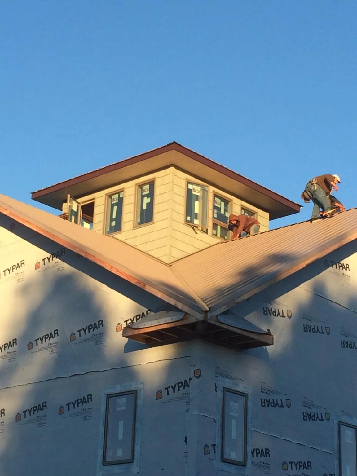 Roofers working around a rooftop cupola on a new metal roof at sunset — Roof Waterproofing in Wawaka by Roofing Brothers